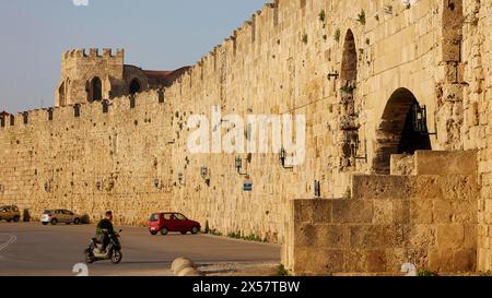 Mur de la vieille ville à côté d'une route avec scooter passant dans le soleil, zone portuaire, ville de Rhodes, Rhodes, Dodécanèse, îles grecques, Grèce Banque D'Images