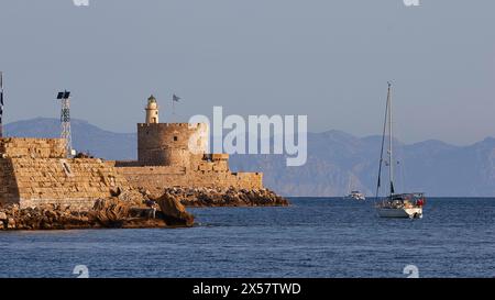 Bateau navigue en face de l'ancienne forteresse avec phare dans la lumière douce du matin, Fort de Saint Nikolaos, zone portuaire, ville de Rhodes, Rhodes, Dodécanèse Banque D'Images