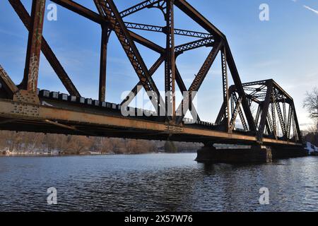 SHERBROOKE, QUÉBEC, CANADA - 29 mars 2023 Pont en acier ferroviaire au-dessus de la rivière Magog au coucher du soleil au printemps Banque D'Images