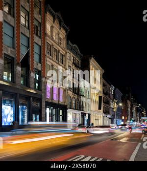 Taxi jaune avec effet de flou de mouvement passant devant les bâtiments historiques le long de Broadway dans le quartier SoHo de New York la nuit Banque D'Images