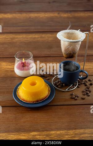 Petit quindim, sucré traditionnel brésilien, à côté d'une tasse de café et d'une bougie 2. Banque D'Images