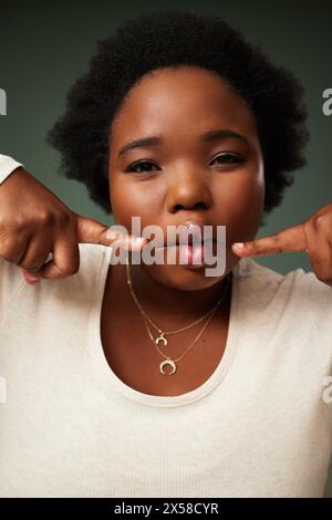 Comique, femme noire et visage de poisson drôle en studio pour la comédie ou la blague isolé sur fond vert. Portrait, lèvres et mannequin fou avec facial Banque D'Images