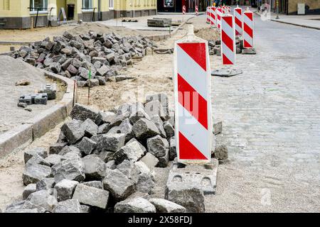 Pavage de rue avec cubes martelés historiques forme des pavés de granit, , cubes roches, cubes pierres, panneau d'avertissement vertical rayé rouge et blanc Banque D'Images