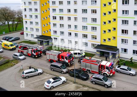 Liepaja, Lettonie- 8 avril 2024 : trois pompiers, police et ambulances devant un grand immeuble, trois services d'urgence sur les lieux Banque D'Images