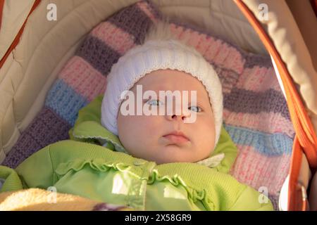 un beau portrait de bébé allongé dans la lumière du soleil à l'automne dans une calèche Banque D'Images