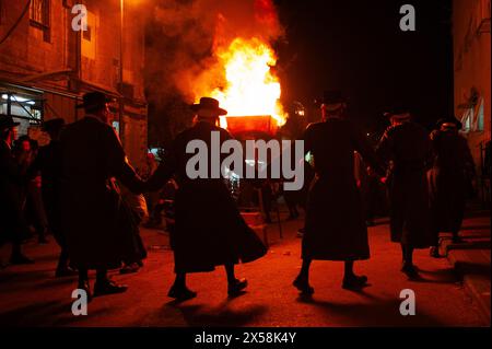 Des hommes juifs orthodoxes chantent et dansent dans la rue près d'un feu de joie lors d'une célébration traditionnelle du Lag B'Omer à Jérusalem, en Israël. Banque D'Images