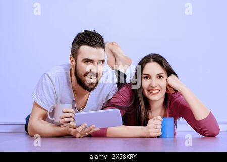 Couple aime un moment de détente, partager des rires et du contenu numérique sur une tablette, leur joie et leur compagnie évidentes Banque D'Images