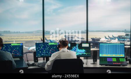 Équipe diversifiée de contrôle du trafic aérien travaillant dans une tour d'aéroport moderne. La salle de bureau est pleine d'écrans d'ordinateur de bureau avec écrans de navigation, données de départ et d'arrivée d'avion pour les contrôleurs. Banque D'Images