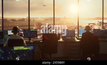 Équipe diversifiée de contrôle du trafic aérien travaillant dans une tour d'aéroport moderne à Sunset. La salle de bureau est pleine d'écrans d'ordinateur de bureau avec écrans de navigation, données radar de vol d'avion pour les contrôleurs. Banque D'Images