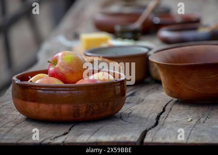 Pommes mûres dans un bol en céramique gros plan, poterie sur une table en bois, style de vie médiéval, nature morte. Photo de haute qualité Banque D'Images