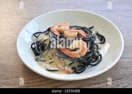 spaghetti à l'encre de calmar noir avec vinaigrette aux crevettes sauce crème carbonara blanche sur l'assiette Banque D'Images