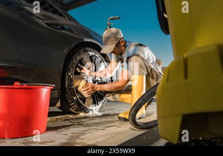 Homme caucasien qui lave sa voiture. Détail des jantes en alliage. Banque D'Images