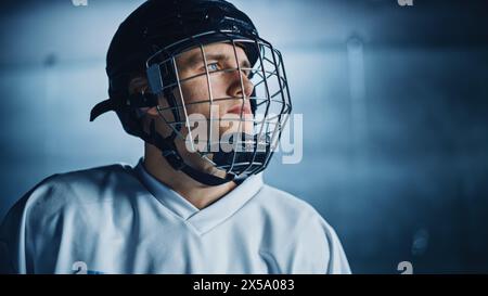 Patinoire de hockey sur glace : Portrait d'un joueur professionnel confiant, portant un masque de cage métallique, regardant au loin. Athlète concentré, déterminé à gagner et à être champion. Portrait Banque D'Images