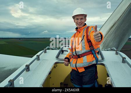 Éolienne, pouces vers le haut et portrait de l'homme dans la maintenance de l'électricité de la production de réseau industriel. Énergie renouvelable, assurance qualité et Banque D'Images