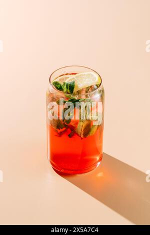 Un verre éclatant de limonade aux baies oranges garnie de menthe fraîche et d'une tranche de citron, parfait pour une chaude journée d'été. Banque D'Images