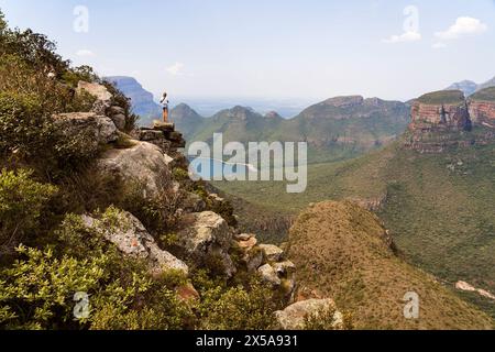Vue arrière d'une femme méconnaissable se tient sur un bord de falaise regardant la vue panoramique de Blyde River Canyon en Afrique du Sud, entouré de verdure luxuriante Banque D'Images