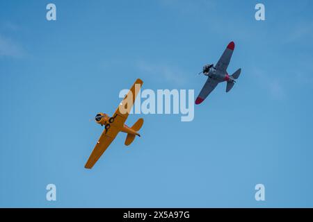 D'en bas, deux avions vintage volent contre un ciel bleu clair lors d'un spectacle aérien, capturé sous un angle bas. Banque D'Images