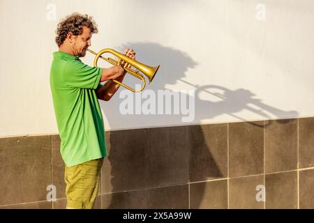 Vue latérale d'un spectacle inspirant d'un homme à un bras jouant habilement de la trompette avec détermination et joie dans une rue urbaine Banque D'Images