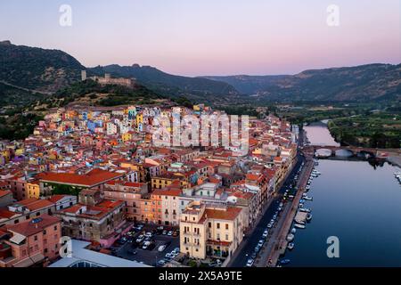 Une vue aérienne pittoresque d'une ville vibrante et colorée en Sardaigne, Italie pendant la douce lumière du crépuscule, avec une rivière sereine qui coule à côté Banque D'Images