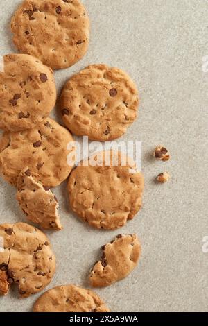 Image vue de dessus de biscuits aux pépites de chocolat avec des marques de morsure visibles, dispersées sur une toile de fond texturée Banque D'Images