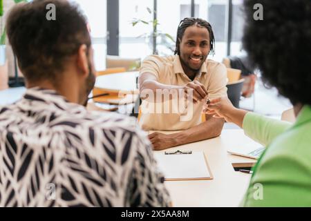 Groupe diversifié de professionnels engagés dans une réunion productive avec un accent sur l'homme qui remet une clé à un collègue dans un espace de coworking Banque D'Images