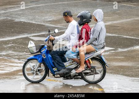 SAMUT PRAKAN, THAÏLANDE, 20 mars 2024, le trio conduit une moto ensemble sous la pluie Banque D'Images