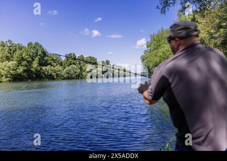 Hartheim, Allemagne. 08 mai 2024. Le pêcheur Johannes Reimchen, 40 ans, se tient avec sa canne à pêche sur les rives du Rhin près de Hartheim et des poissons. Les météorologues s'attendent à beaucoup de soleil dans le sud-ouest pour le long week-end entre le jour de l'Ascension et la fête des mères. Crédit : Philipp von Ditfurth/dpa/Alamy Live News Banque D'Images