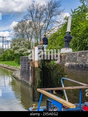 Grand Union canal main Line, Calcutt Locks, Angleterre – Un bateau étroit dans l'écluse supérieure avec les portes d'écluse fermant par une journée d'été ensoleillée brillante contre un ciel bleu Banque D'Images