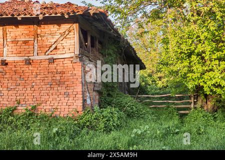 Vieille clôture en bois dans le village et vieille maison rurale en briques Banque D'Images