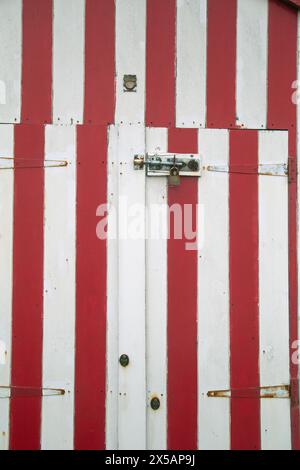 Great Yarmouth, Angleterre, avril 2024, un gros plan en format portrait de panneaux colorés sur une cabane de plage peinte à rayures rouges et blanches Banque D'Images