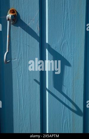 Norfolk, Angleterre, 30 avril 2024, gros plan de panneaux de bois peints en bleu sur une cabane de plage avec un crochet en métal fixé Banque D'Images