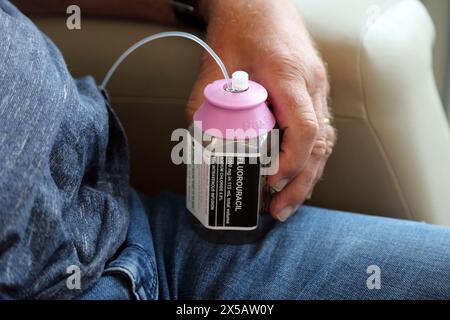 Homme traité avec du chlorure de sodium Fluorouracil médicament cytotoxique pour perfusion intraveineuse continue médicament de chimiothérapie à la maison par Picc Line dans le bras supérieur - traitement pour cancer Surrey Angleterre Banque D'Images