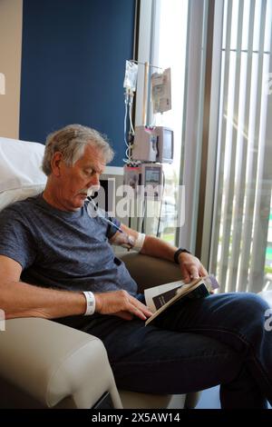 Cancer patient Reading Book tout en ayant un traitement de chimiothérapie avec perfusion intraveineuse pompe de chimiothérapie Surrey Angleterre Banque D'Images