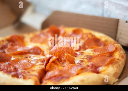 Une pizza pepperoni, un aliment de base dans la cuisine de restauration rapide, repose dans une boîte en carton. Ce plat de boulangerie est une recette classique de pizza californiastyle Banque D'Images