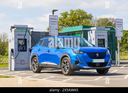 Voiture électrique Peugeot en cours de charge à une borne de recharge InstaVolt EV., Suffolk. ROYAUME-UNI Banque D'Images