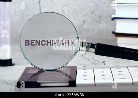 Concept commercial de benchmark. Un REPÈRE DE mot écrit à travers une loupe sur un fond gris. Image en noir et blanc Banque D'Images