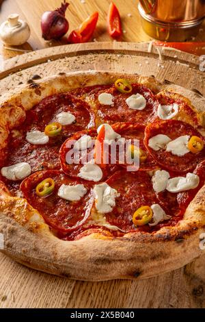 Pizza pepperoni épicée avec garnitures sur table en bois Banque D'Images