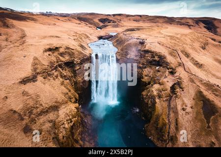 Vue aérienne par drone de Majestic puissante cascade Skogafoss coulant de falaise parmi la montagne brune en automne au sud de l'Islande Banque D'Images