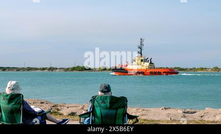 PORT ARANSAS, TX - 28 fév 2020 : les personnes âgées regardant un remorqueur orange et jaune, le CC LA QUINTA naviguent sur l'eau sur le canal du navire à Corp Banque D'Images