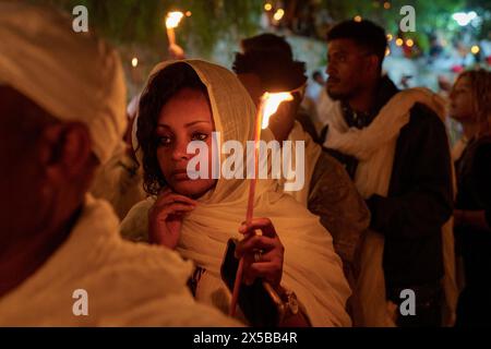 Une éthiopienne tient une bougie pendant la cérémonie du feu sacré de l'Église orthodoxe éthiopienne à Jérusalem. La cérémonie du Saint feu est célébrée par les églises orthodoxes de l'église du Saint-Sépulcre à Jérusalem chaque année avant Pâques. Cet événement spirituel et religieux est l’un des rituels les plus importants du christianisme orthodoxe, et de nombreux pèlerins du monde entier se rassemblent pour en témoigner. Au cours de la cérémonie, le Patriarche grec entre dans les aediculae où se trouve le tombeau de Jésus, priant jusqu'à ce que le feu Saint soit considéré comme allumé par le Saint-esprit. La foule à l'église Wai Banque D'Images