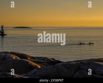 Deux personnes faisant du kayak au coucher du soleil à l'extérieur de Klåva, Hönö, l'archipel de Göteborg, en Suède. Banque D'Images