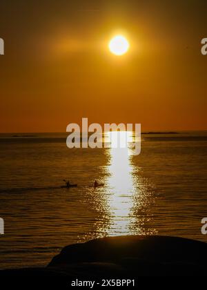 Deux personnes faisant du kayak au coucher du soleil à l'extérieur de Klåva, Hönö, l'archipel de Göteborg, en Suède. Banque D'Images