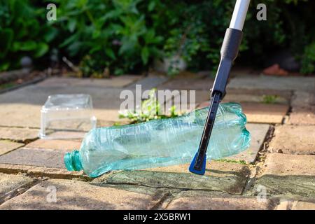 Ramasser les déchets plastiques et les ordures tombées sur le trottoir pour nettoyer et protéger l'environnement Banque D'Images