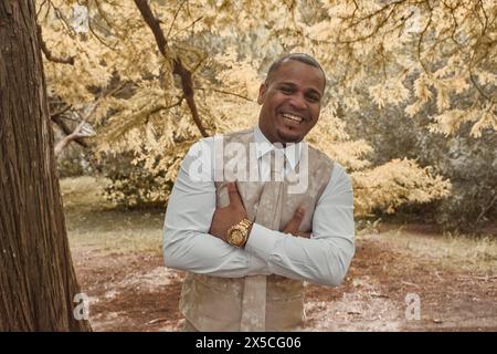 Homme latino souriant à la caméra, il se tient debout, les bras croisés. Concept de saison d'automne, l'homme est heureux. Banque D'Images