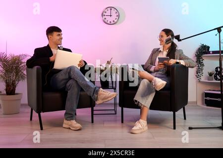 Jeune couple avec microphones enregistrant podcast en studio Banque D'Images