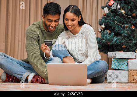 Couple, les gens et Noël avec carte de crédit sur ordinateur portable avec achats en ligne pour la saison des fêtes, cadeau et cadeaux. Relation, amour et maison avec Banque D'Images