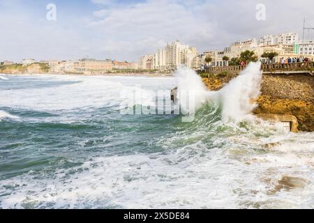 Une vague s'écrasant contre le rocher jaune sur le front de mer dans une forte tempête, avec les bâtiments de la ville en arrière-plan. Biarritz, France. Banque D'Images