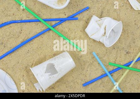 Plage d'été après le festival ou la fête : tasses et pailles en plastique. Vue de dessus. Banque D'Images