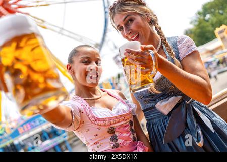 Deux femmes en robes traditionnelles tracht grillent joyeusement des tasses à bière à oktoberfest ou duld en allemagne Banque D'Images