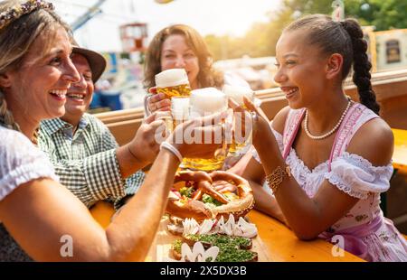 Quatre amis dans la tente de bière à Dult ou Oktoberfest toast avec des tasses de bière dans l'air Banque D'Images